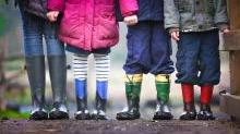 Imagen de pies de niños con botas de agua y ropa de abrigo